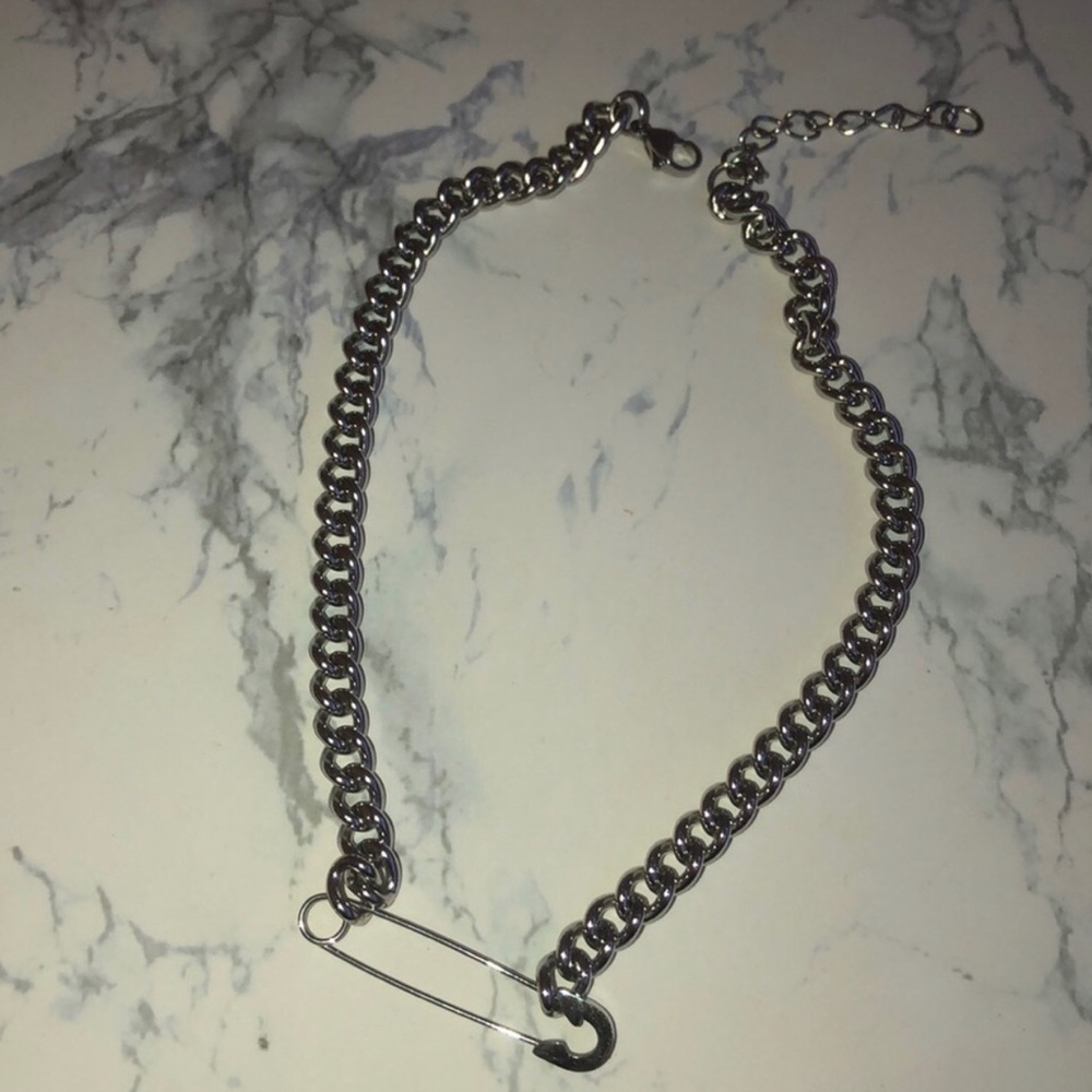 Silver chain choker with a pin on it